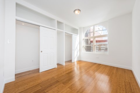 a living room with wood floors and white walls and a window