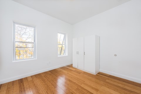 a living room with white walls and wood floors and a closet