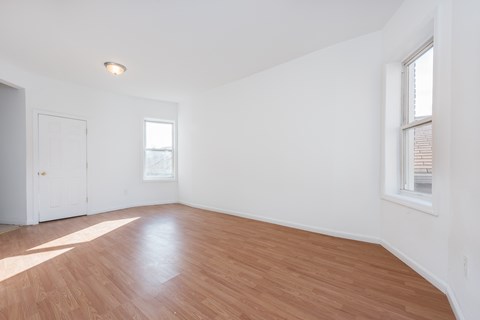 an empty living room with wood floors and white walls