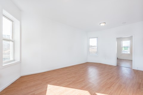 an empty living room with wood floors and white walls
