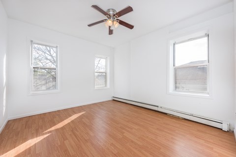 an empty room with wood floors and a ceiling fan