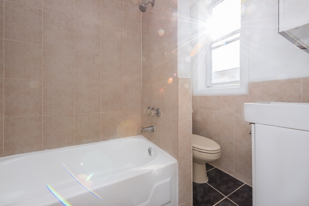 a bathroom with a tub and a toilet and a window