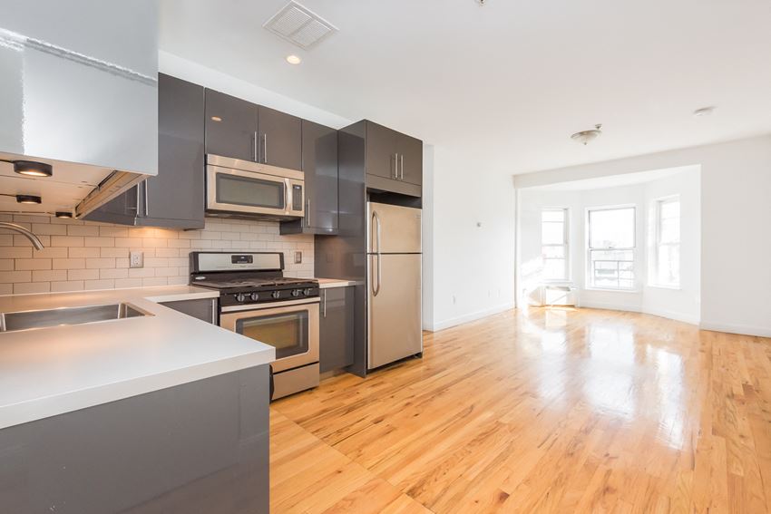 an empty kitchen with stainless steel appliances and a wood floor
