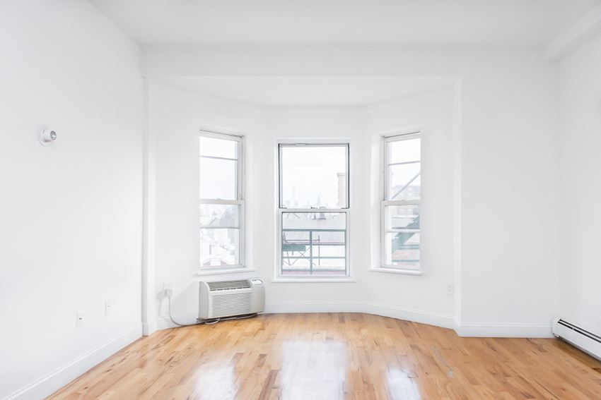 an empty living room with three windows and a wood floor