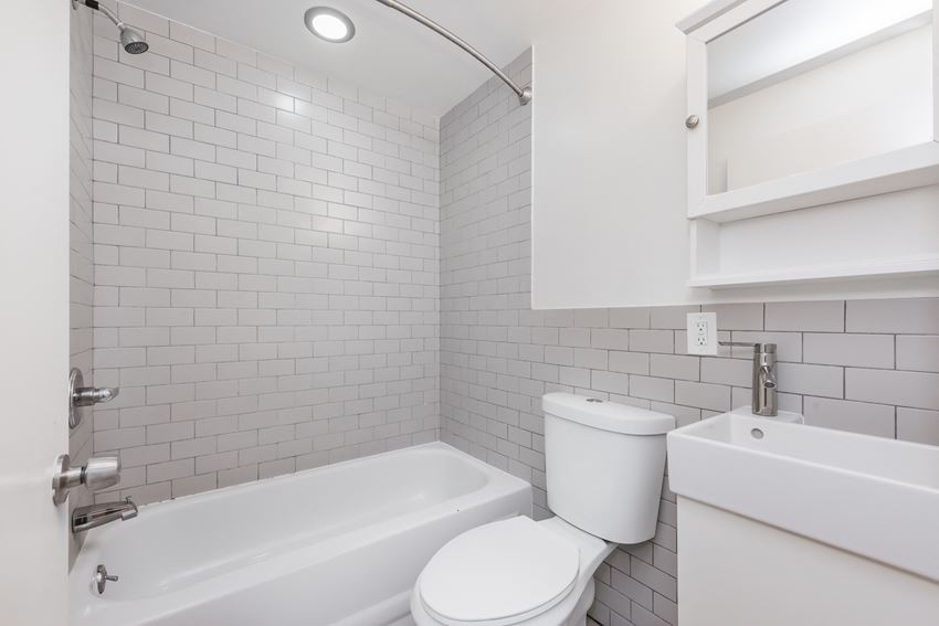 a white bathroom with a white toilet and tub and a sink