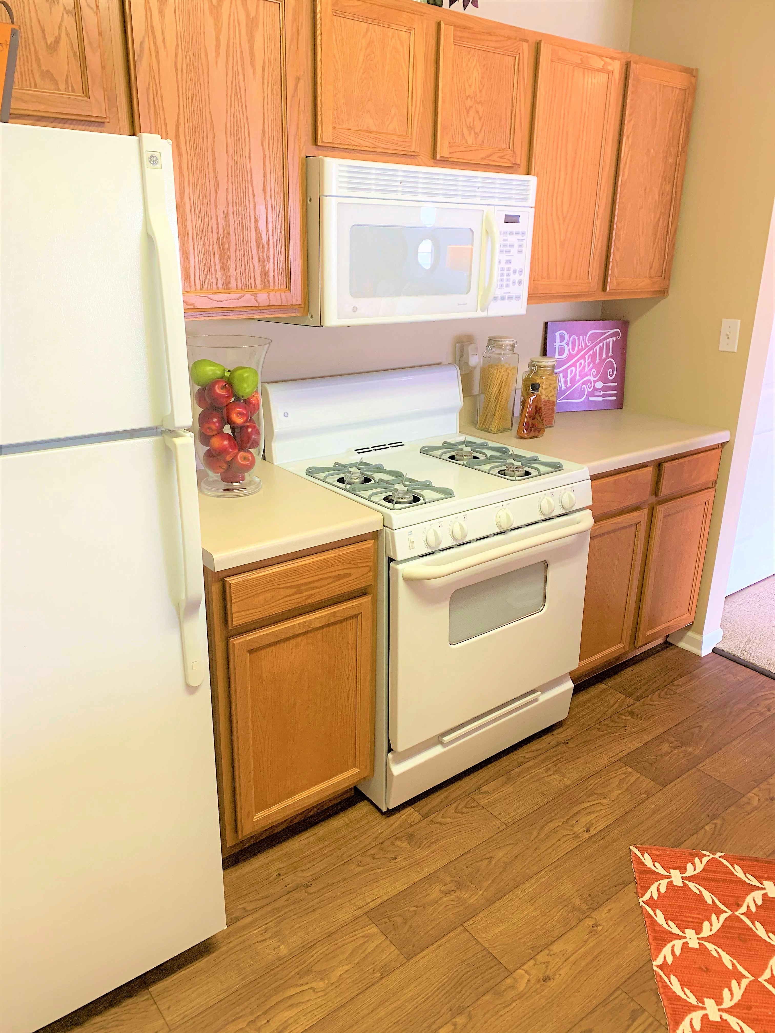 A kitchen with wooden cabinets and a white stove top oven.