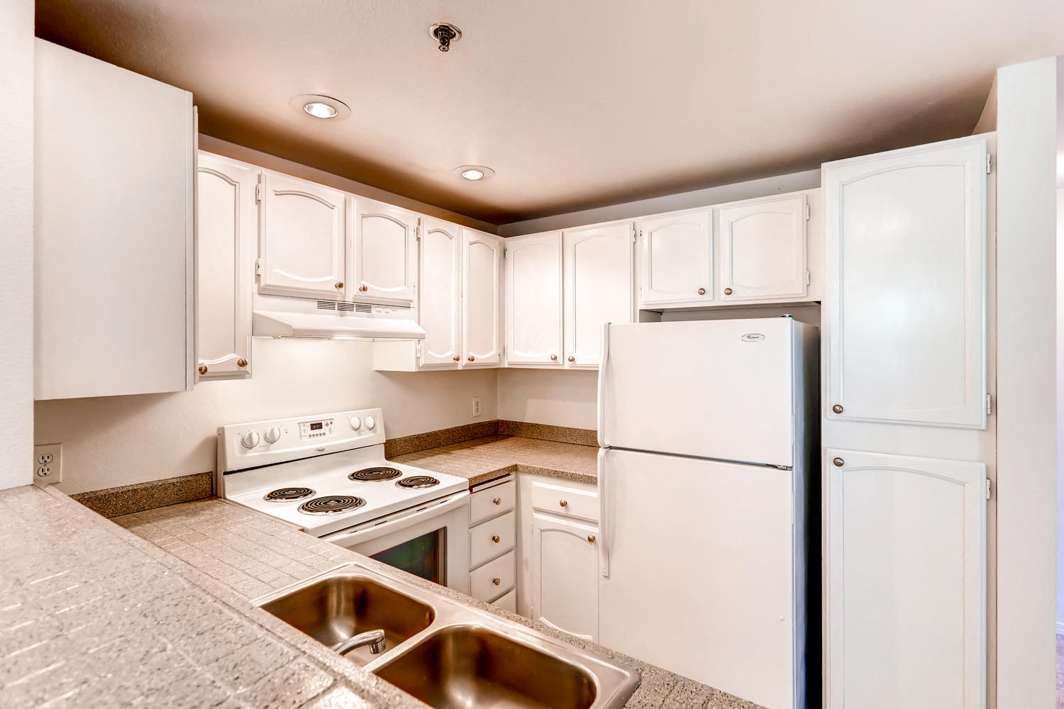 a kitchen with white cabinets and a white refrigerator