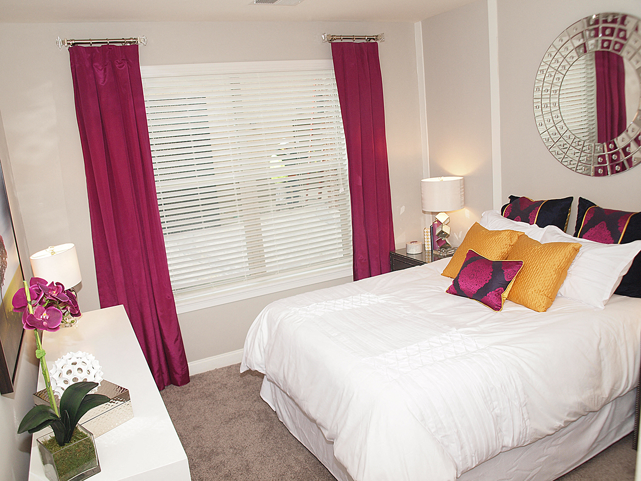a bedroom with a white bed with red curtains and a large window