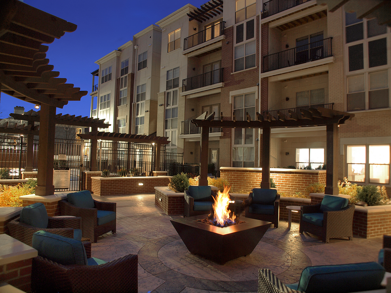 an outdoor lounge area with a fire pit at night