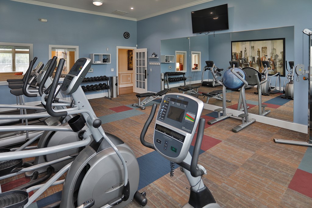 a gym with exercise equipment and a television