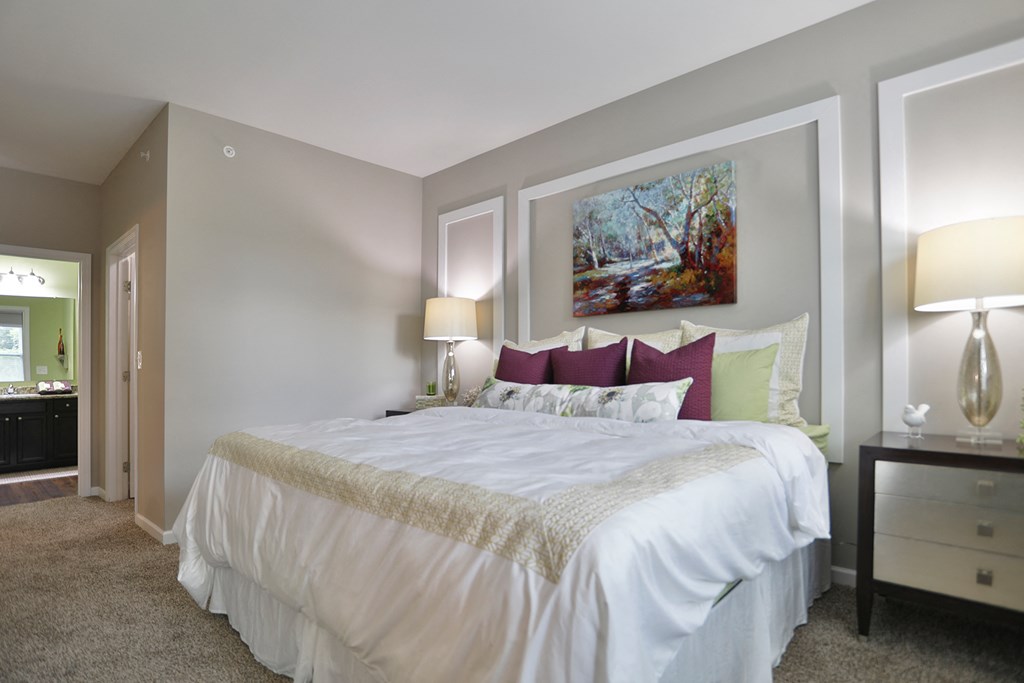 a bedroom with a white bed and a painting on the wall