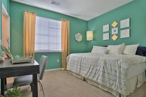 a bedroom with green walls and a bed and a desk with a chair