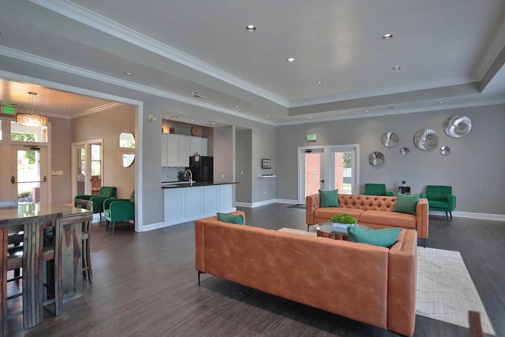A living room with a brown couch and green chairs.