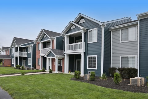 A row of houses with balconies and front yards.