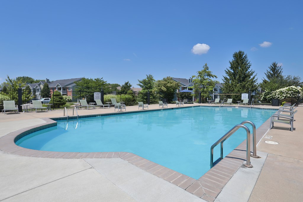 A large outdoor swimming pool with a metal ladder and steps leading into the water.