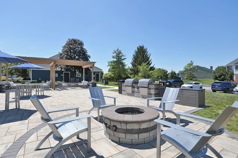 A fire pit is surrounded by chairs in a patio setting.