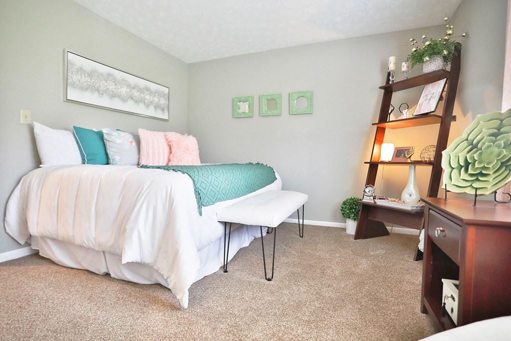 a bedroom with a bed with white sheets and pillows and a shelf with a