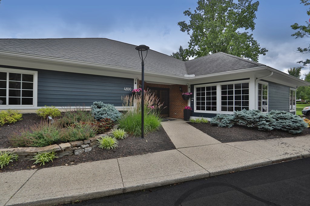 a sidewalk in front of a blue house with a porch