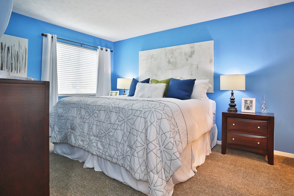 a bedroom with a bed and blue walls and a window