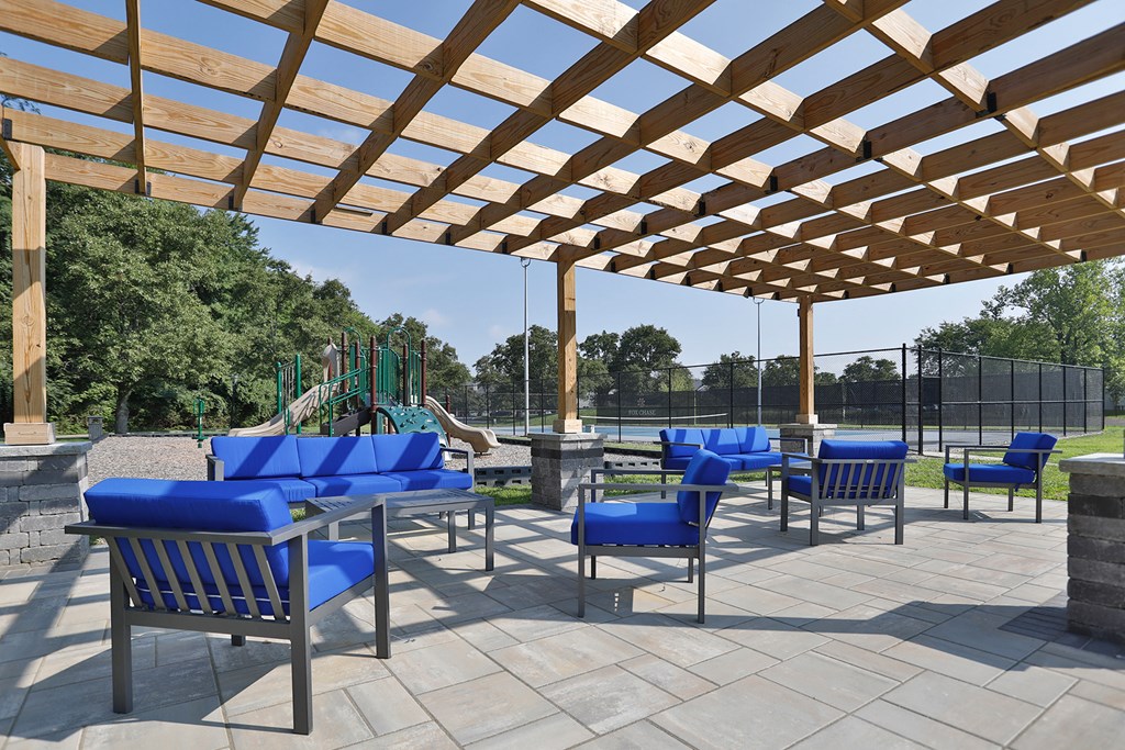 a patio with blue chairs and a wooden canopy