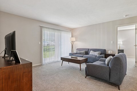 A living room with a grey couch and a television on a wooden cabinet.