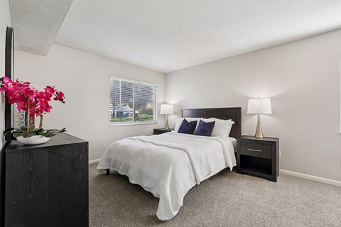 A bedroom with a large bed and a nightstand with a lamp.
