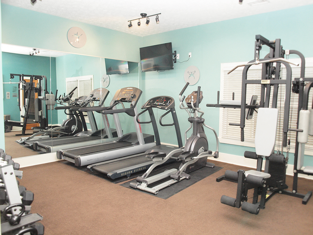 a gym with cardio equipment and a tv on the wall