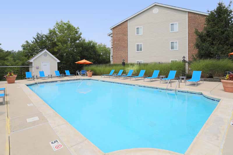 a large swimming pool with blue chairs around it