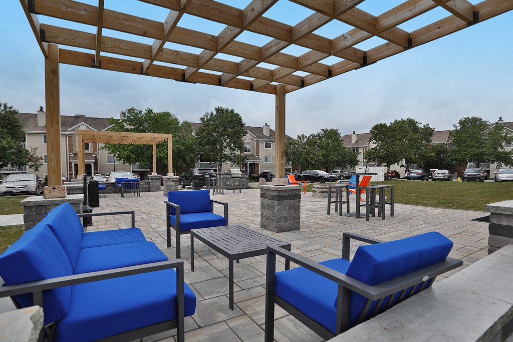 a patio with blue chairs and tables under a wooden roof