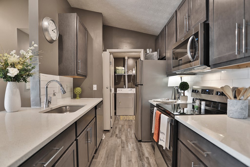 an open kitchen with stainless steel appliances and white counter tops