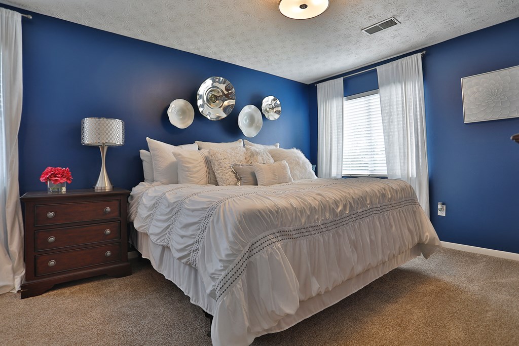a bedroom with blue walls and a bed with white sheets and pillows