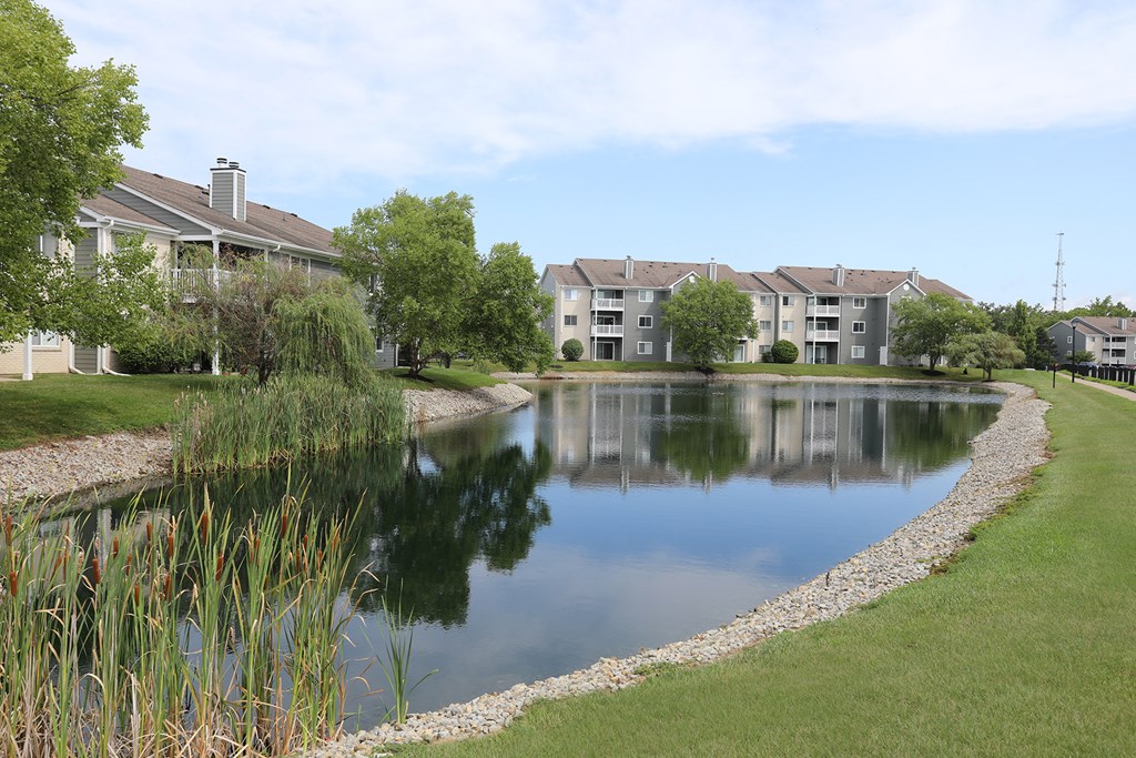 an apartment complex with a pond in front of it