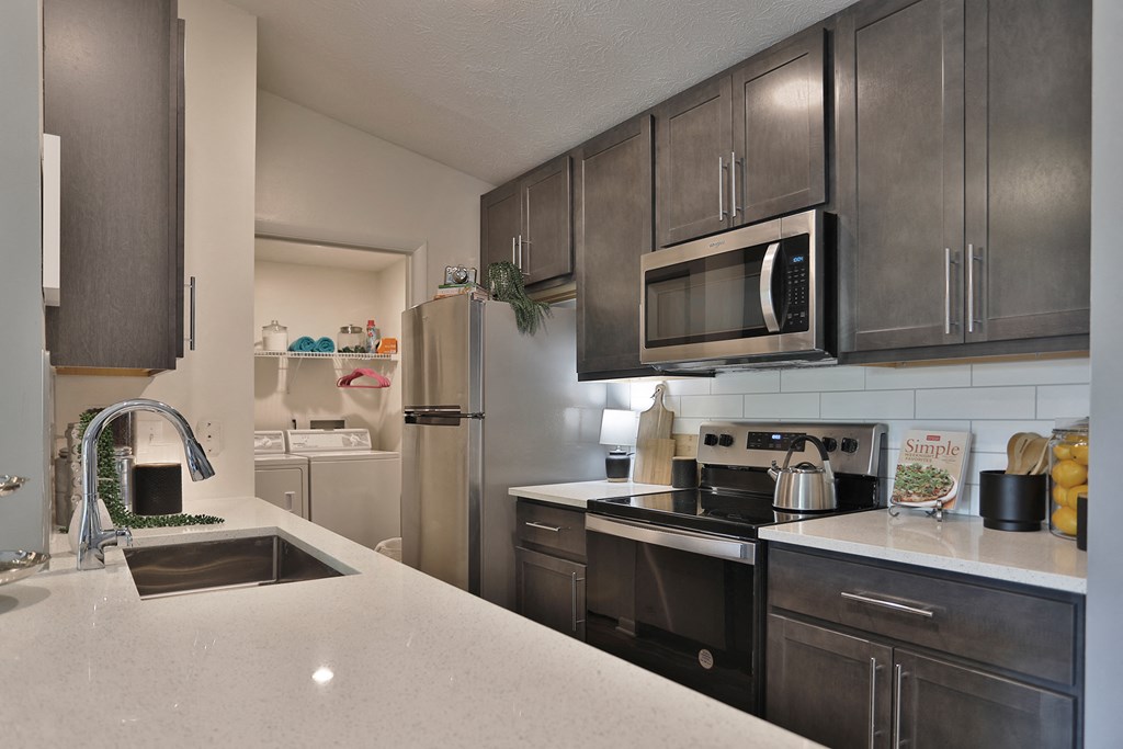 an updated kitchen with stainless steel appliances and white counter tops