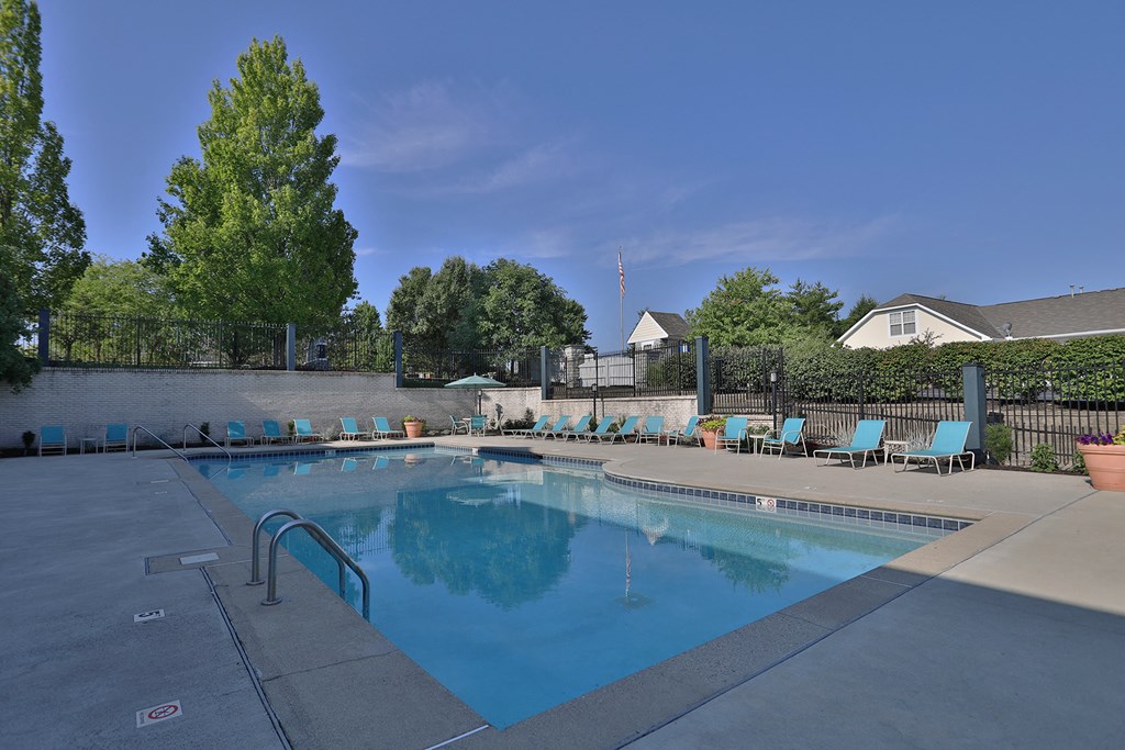 a swimming pool with chairs and a fence around it