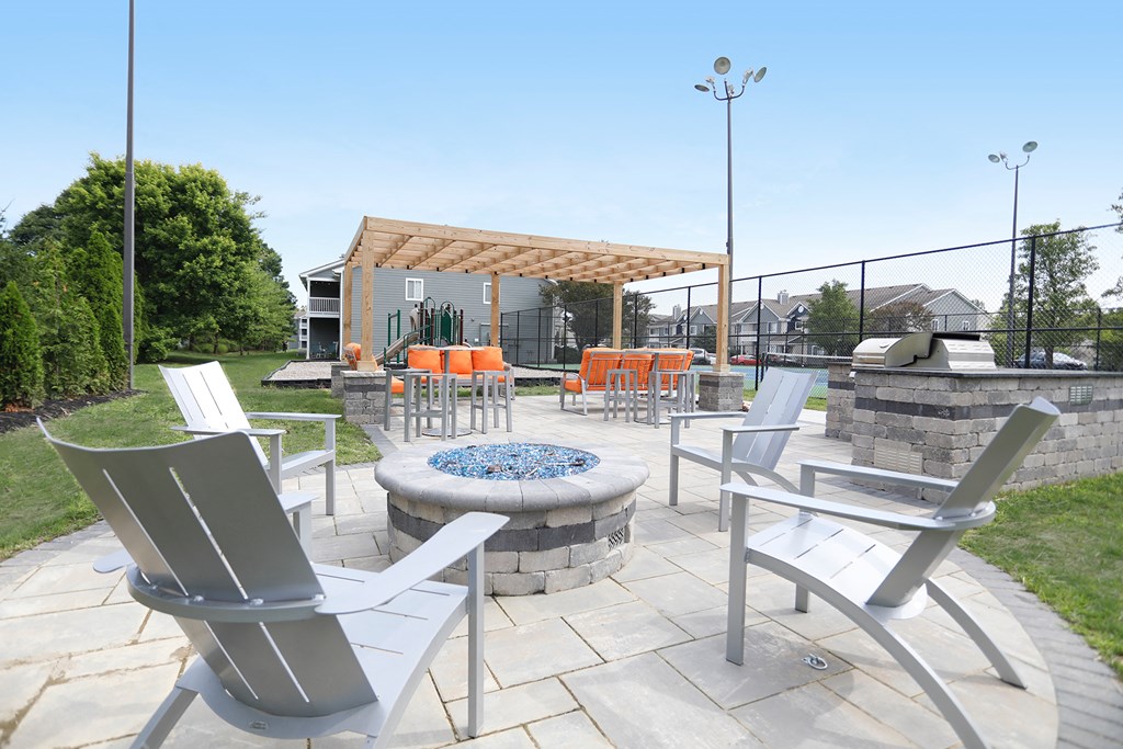 a patio with chairs and tables and a fire pit