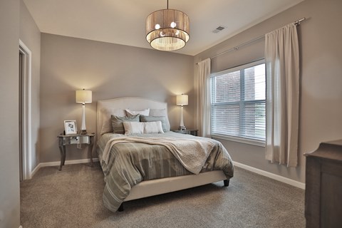 A bedroom with a large bed and a chandelier.