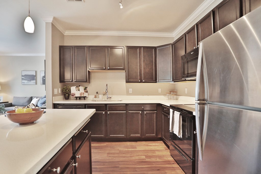 A modern kitchen with dark brown cabinets and a stainless steel refrigerator.