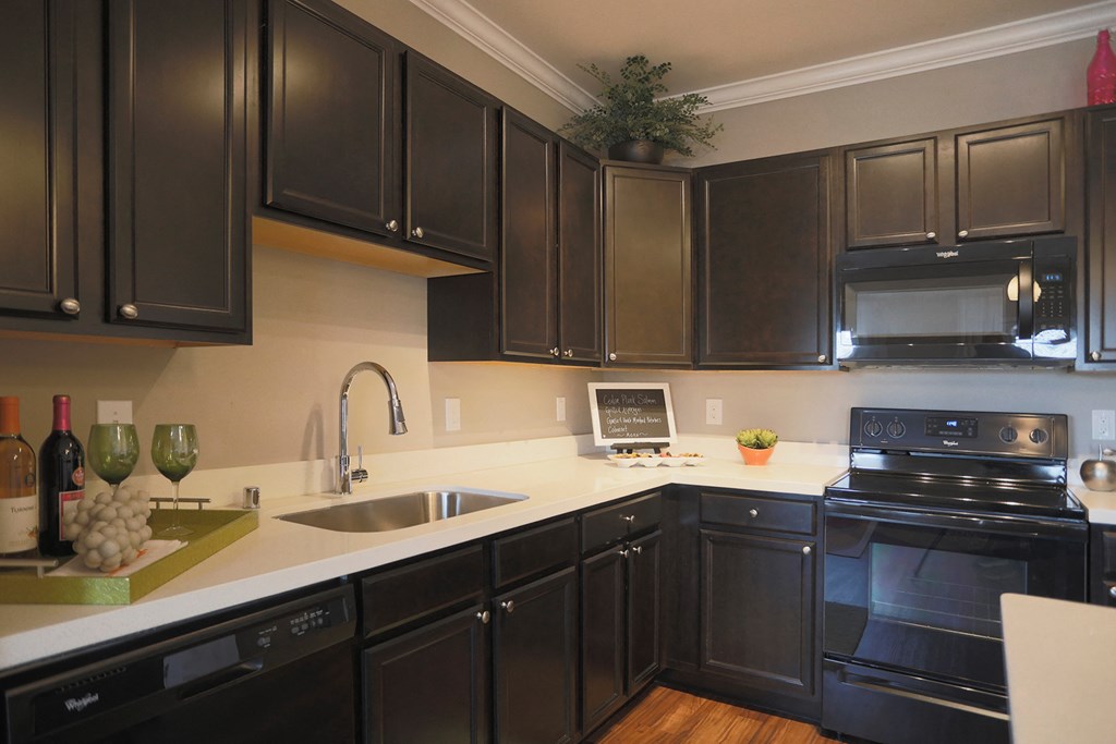 a kitchen with black cabinets and white counter tops and a sink
