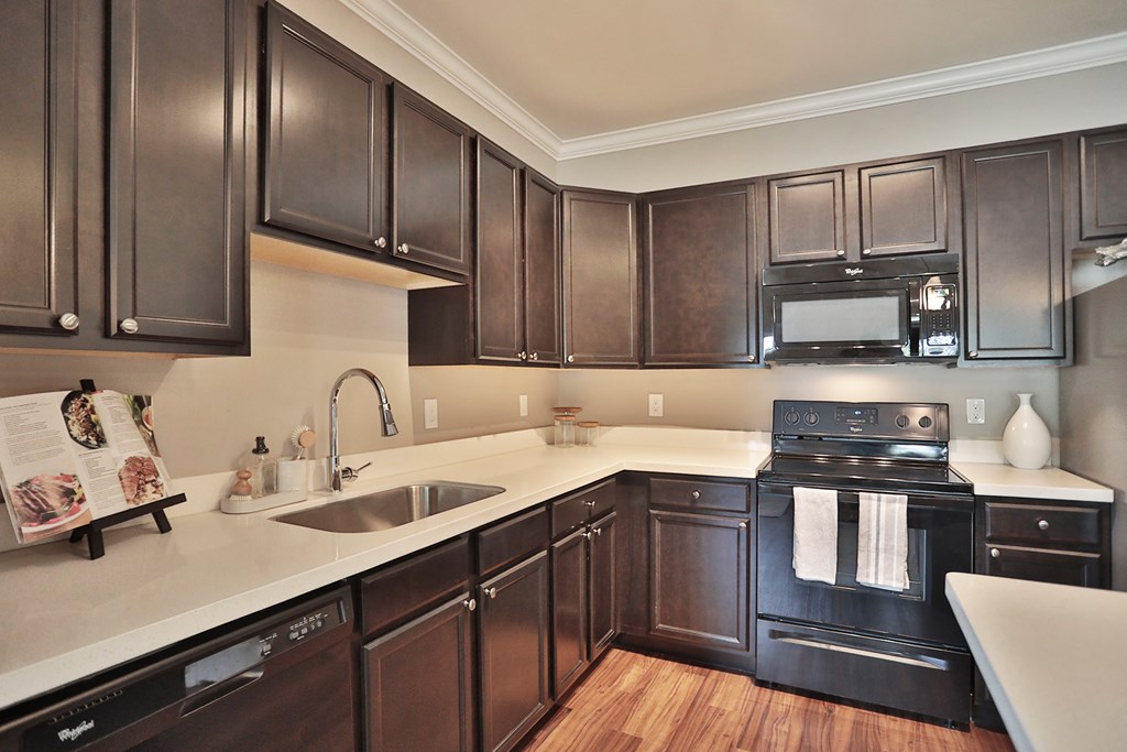 A kitchen with dark wood cabinets and a white countertop.