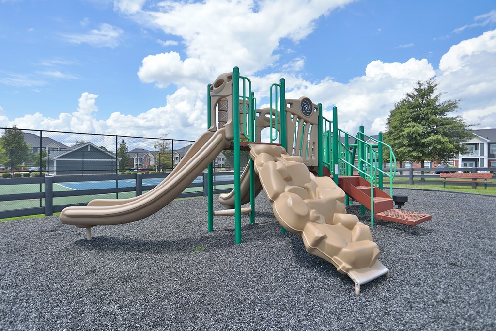 A playground with a green slide and a brown slide.