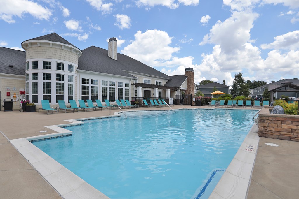 A large swimming pool in front of a building with a white roof.