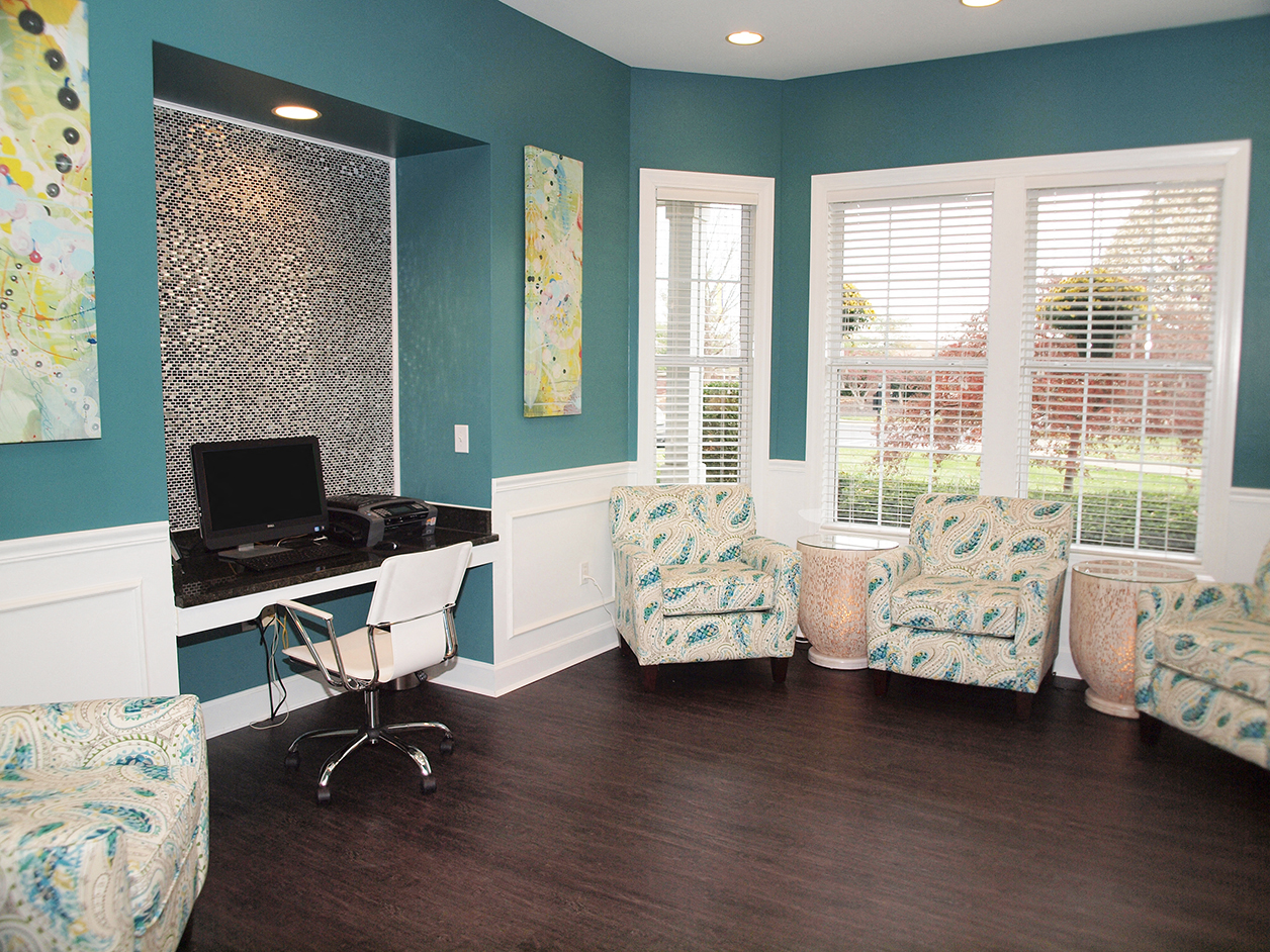 a living room with a desk and chairs and a window