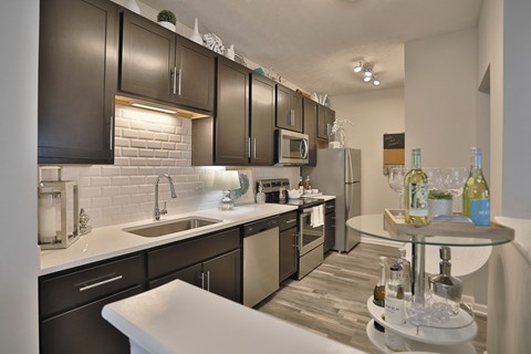 A modern kitchen with dark brown cabinets and a white countertop.