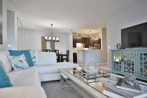 A modern living room with a white couch and a glass coffee table.