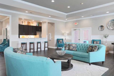 a living room with blue couches and a kitchen with a bar
