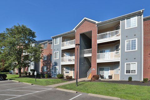 A large apartment building with a parking lot in front.