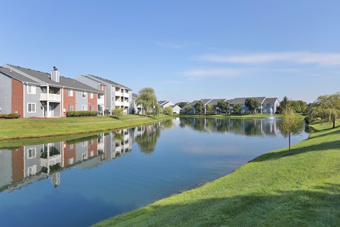 A row of houses are reflected in the water of a lake.