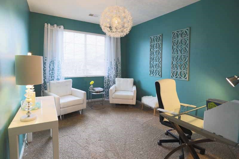 a living room with a desk and chairs