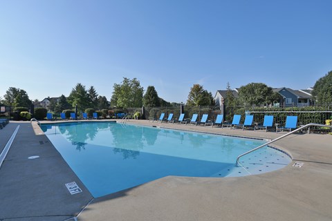 A large outdoor swimming pool with blue water and lounge chairs.