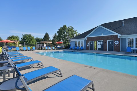 A pool with blue lounge chairs and a building in the background.